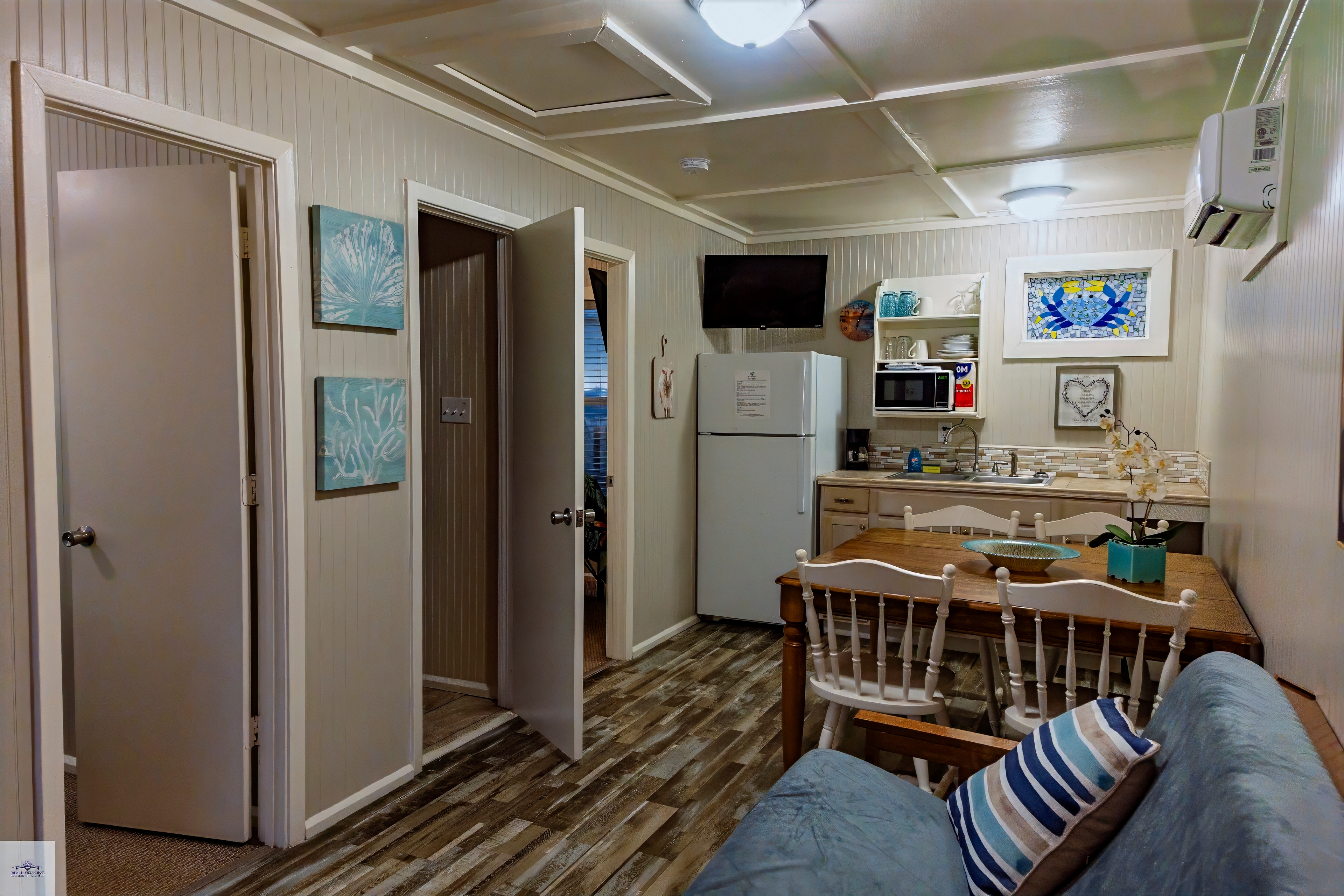 Two bedroom suite dining table, kitchenette, and futon, showing open doorways leading to adjacent rooms.