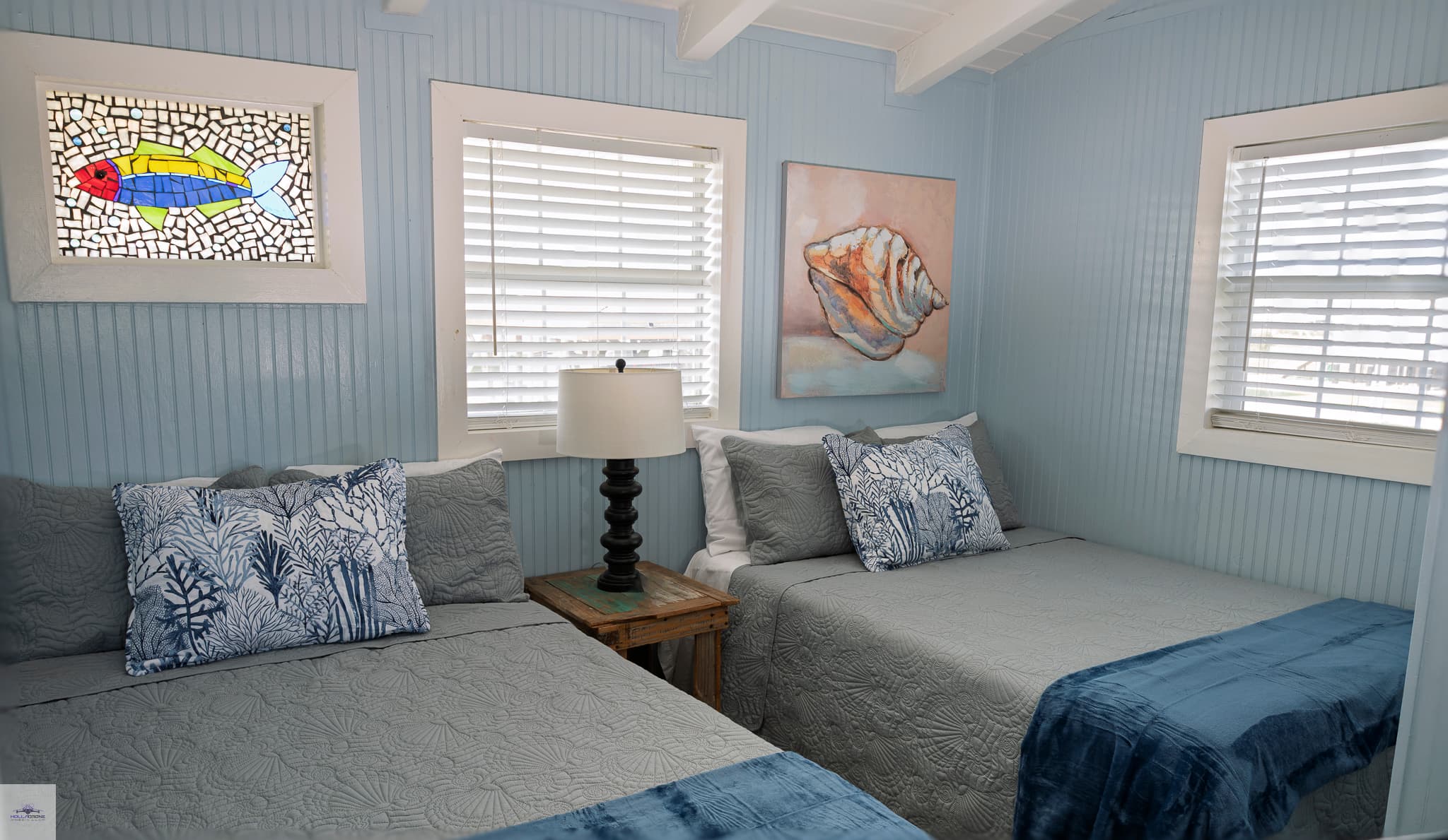 A bedroom with 2 double beds, and a fish stained glass window.
