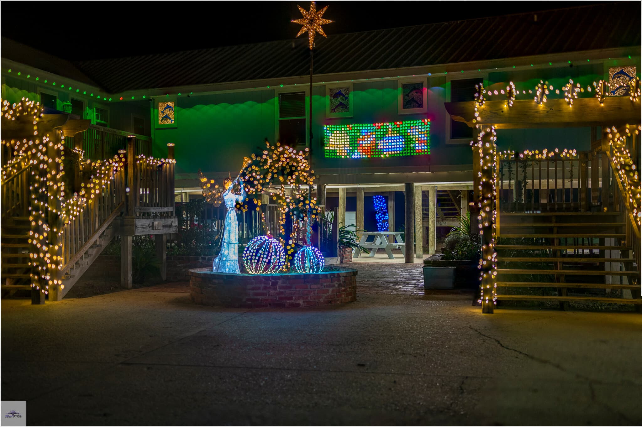 A festive courtyard decorated with colorful holiday lights and a star at night.