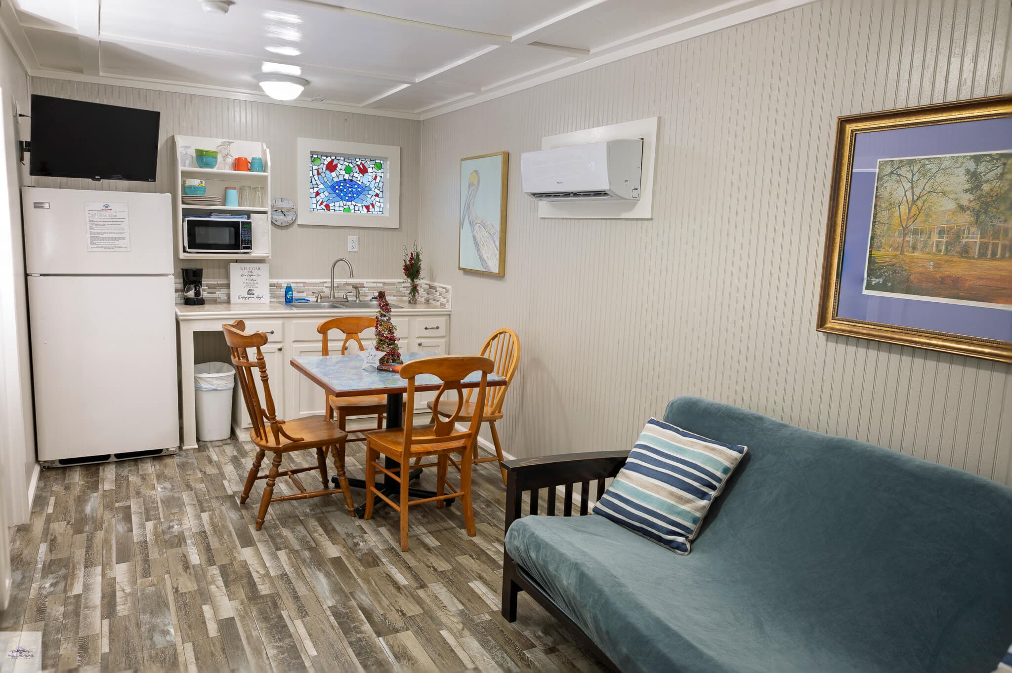 Cozy interior of a kitchenette with dining table, two chairs, a sofa, and a fridge.