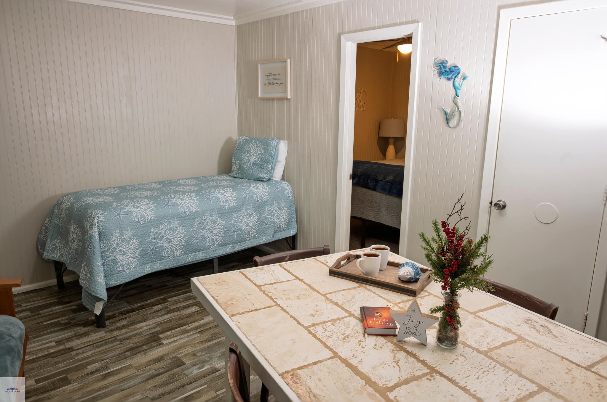 A cozy, decorated room featuring a bed, dining table, and a doorway leading to another space.