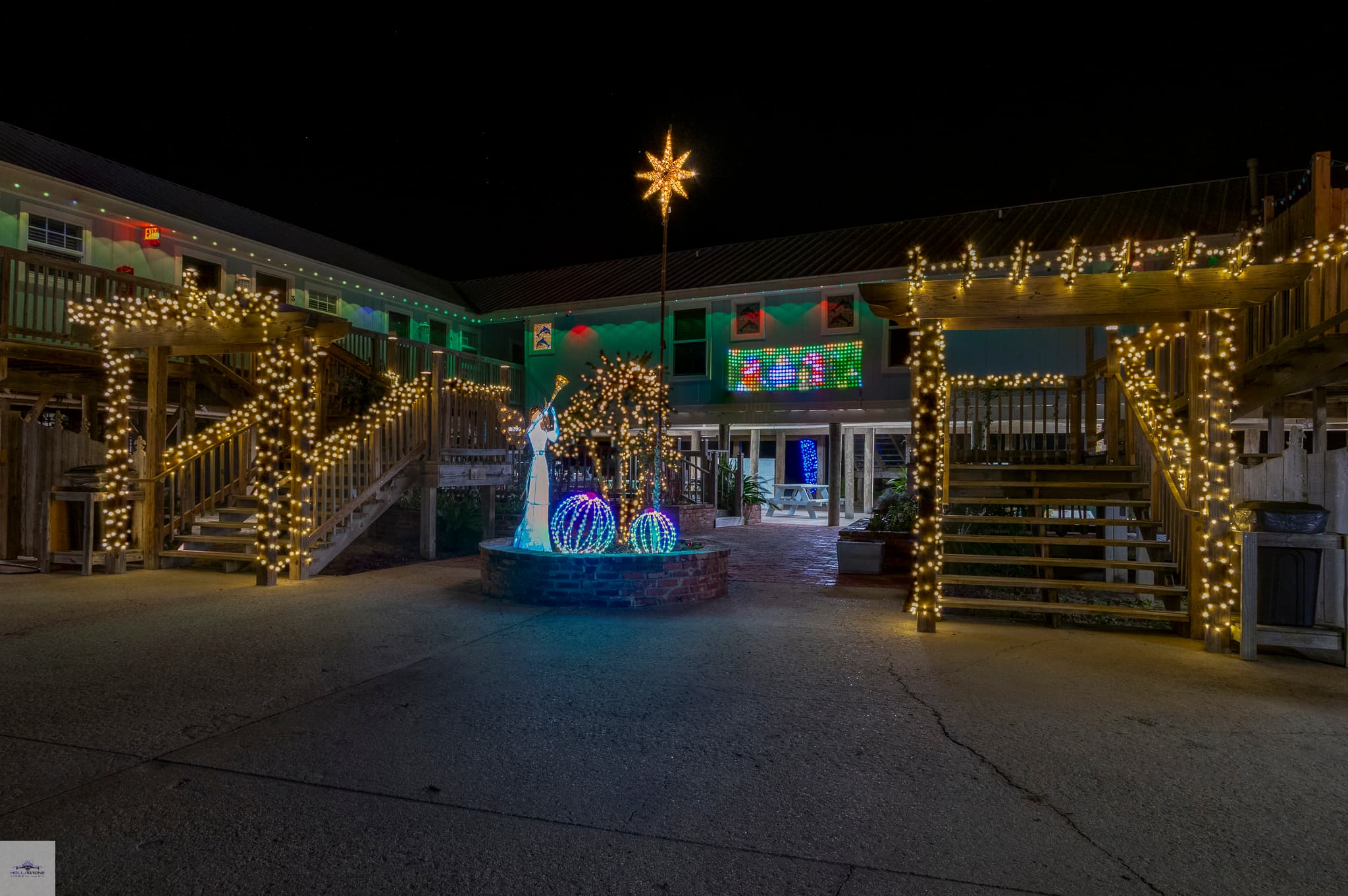 A festive courtyard illuminated with holiday lights and decorations at night.