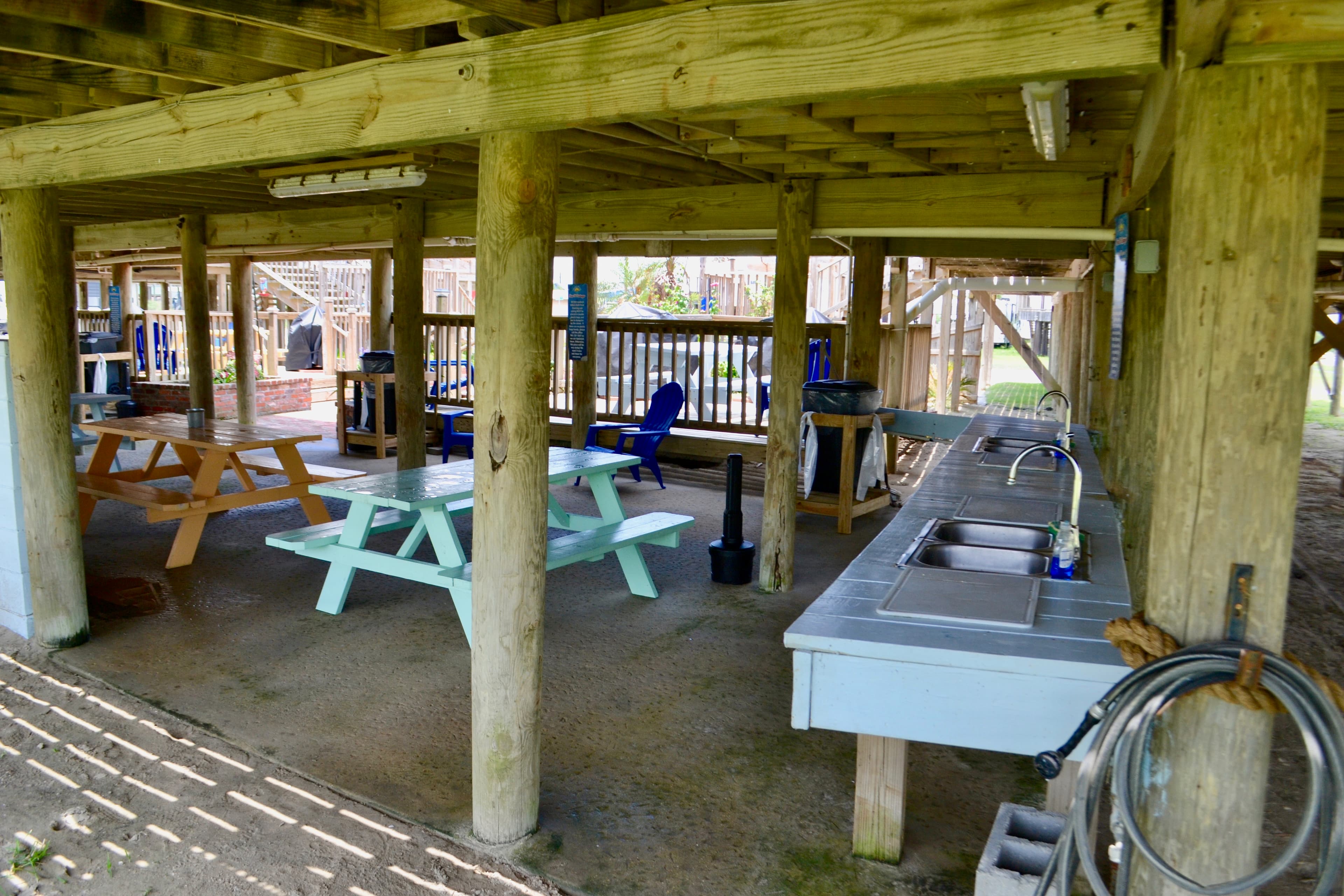 Covered outdoor space featuring picnic tables and a kitchen area with sinks.