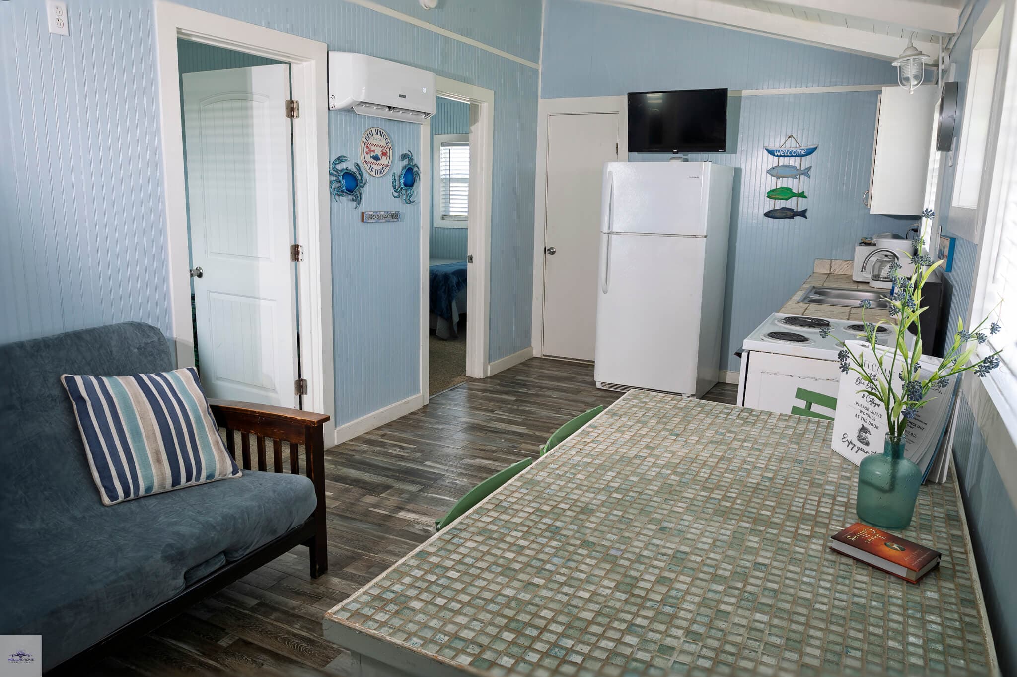 A cozy, light blue kitchen and dining area with a table, refrigerator, and seating.